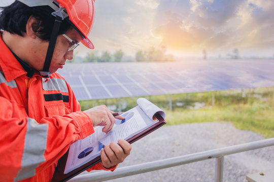 Electrical and instrument technician make a note statistic chart electric system at solar panel field
