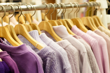 Obraz premium Multicolored knitted sweaters hang on hangers in the store