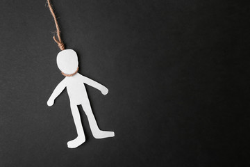 Paper human figure with noose around neck on dark background. Suicide awareness concept