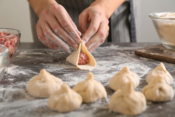 Woman making Chinese dumplings in kitchen, closeup