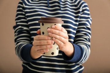 Young woman with cup of hot coffee on color background