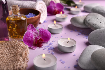Beautiful spa composition with burning candles and stones on color background