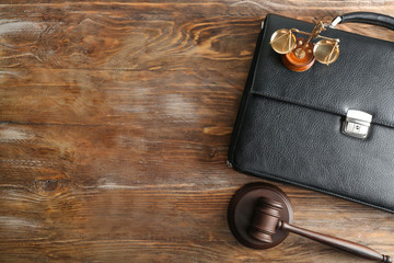 Judge's gavel, briefcase and scales of justice on wooden background