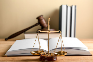 Scales of justice and open book on wooden table