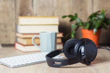 Headphones, keyboard, stack of books and cup on the office desk. Office concept, work day, hourly pay, work schedule, work in a call center.
