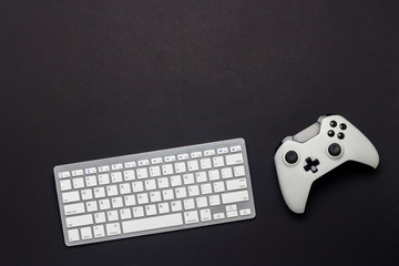 Keyboard and gamepad on a black background. The concept of the game on the PC, gaming, console. Flat lay, top view. © Alex