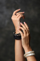 Hands of young woman with stylish bijouterie on dark background