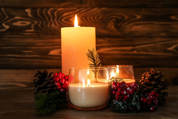 Beautiful burning candles with Christmas decor on wooden table