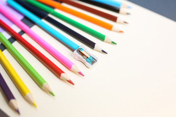 Colour pencils with sharpener lying on pastel beige background. Back to school concept. Colorful art studying and painting process. Drawing with pencils. Copy space place for postcard wish.