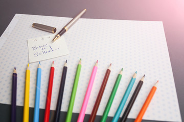 Color pencils lying on cute spotted background with dots. Back to school concept and sign written with a pen. Colorful art studying and painting process. Copy space place for postcard wish.