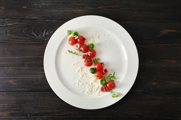 Plate with tomatoes and cheese on dark wooden background