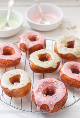 Homemade donuts decorated with colored icing and colored sugar on a light background.