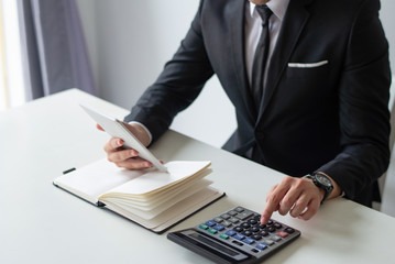 Accountant planning budget. Closeup of business leader using calculator, tablet and notebook at workplace. Accounting concept