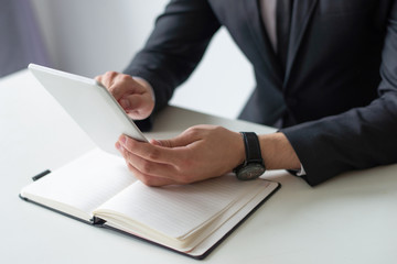 Businessman testing new app. Closeup of man in suit using tablet at his workplace. Application development concept