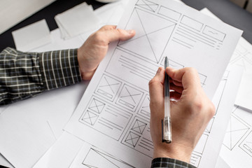 UX website designer drawing wireframe sketch of prototype, framework, layout future project. Creative user experience concept website template. Designer workspace