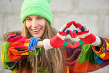Beautiful woman wearing hand and gloves and making heart symbol from fingers