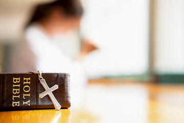 Holy bible and cross on table with Christian woman hoping for better. Asking God for good luck,...