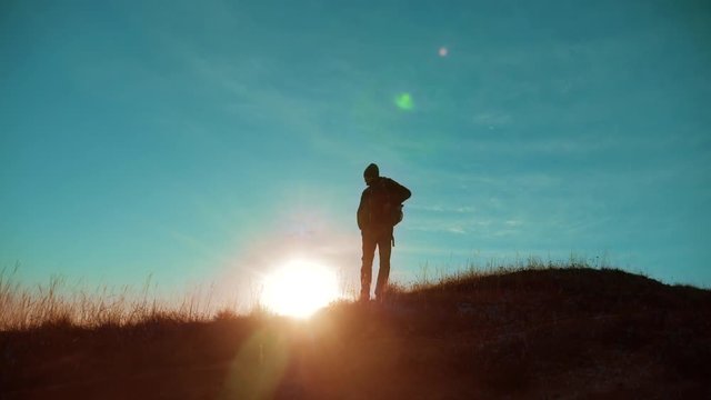 Male man worth it tourist with backpack on the top of the mountain. smartphone navigation. sunlight stands on top of a mountain. slow motion video. man silhouette at sunset . hikers adventure
