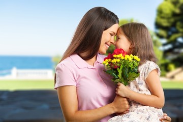 Young woman with little girl and beautiful flowers at room