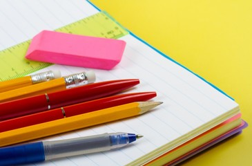 Writing Utensils on the Open Notepad on the Yellow Background