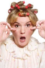 Humorous portrait of old-fashioned grotesque housekeeper with hair curlers and shocked expression