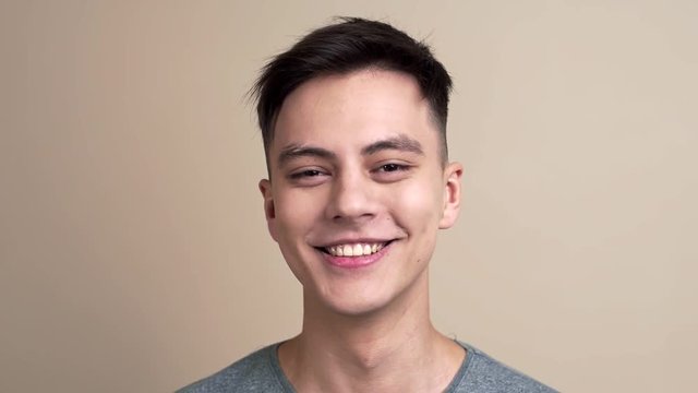 Pretty young guy smiles and laughs to the camera in slow motion, video portrait of a man, selfie video portrait, blogger smiles to the camera