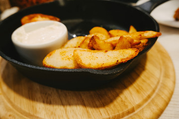 Roasted potato in frying pan on wooden background