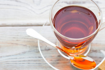 Black tea ceremony - glass full of tea, sugar, yellow lemon, tea leaves, spices on a wooden boards background