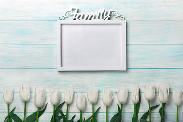 A bouquet of white tulips with a frame for inscription on blue boards
