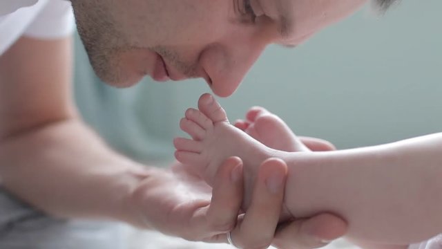 Close up shot of father kissing feet of baby