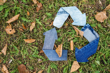 Fototapeta premium Recycle symbol made from textile over green grass background