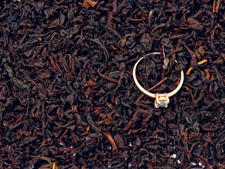 background of black tea leaves. precious ring. decorations.