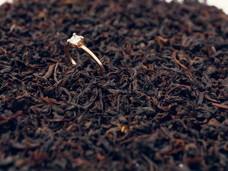 background of black tea leaves. precious ring. decorations.