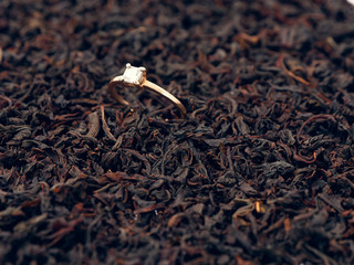 background of black tea leaves. precious ring. decorations.