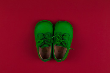 green baby shoes isolated on red background