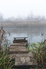 A place for fishing by the river. Foggy autumn morning and frost on plants.