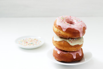 Homemade donuts decorated with colored icing and colored sugar on a light background.