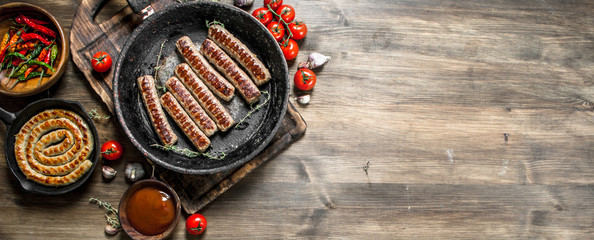 Fried sausages in a pan with sauce.