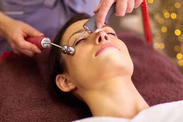 Obraz na płótnie Canvas people, beauty, cosmetology and technology concept - beautiful young woman having needle free mesotherapy or hydradermie facial treatment by microcurrent firming device in spa