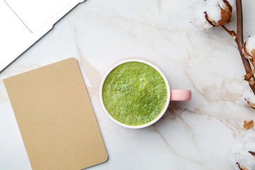 Cup of healthy matcha tea and notebook on table