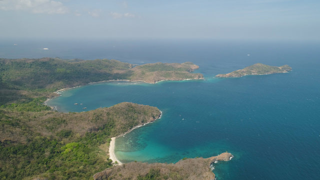 Aerial view of coast with beaches, island Limbones, lagoons and coral reefs. Neela cove, Philippines, Luzon. Coast ocean with turquoise water. Tropical landscape in Asia.