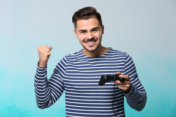 Fototapeta na wymiar Happy young man after winning video game on color background