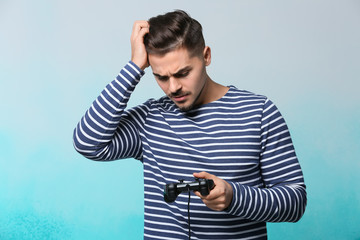 Young man after losing video game on color background