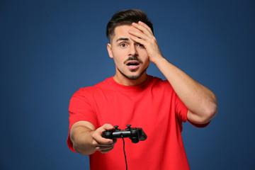 Young man after losing video game on color background