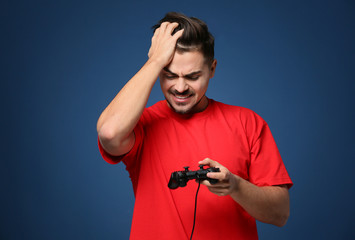 Young man after losing video game on color background