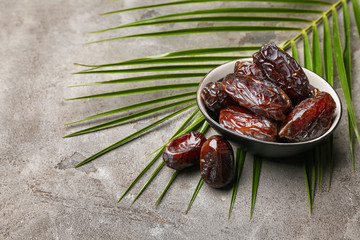 Bowl with sweet dried dates on grey background