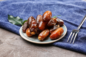 Plate with sweet dried dates on table