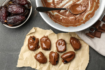 Sweet dried dates covered with chocolate on grey background