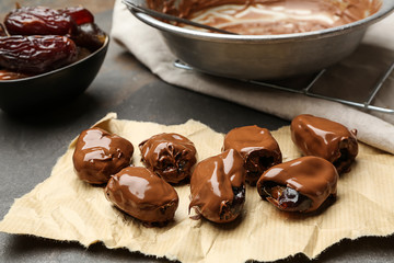 Sweet dried dates covered with chocolate on grey background