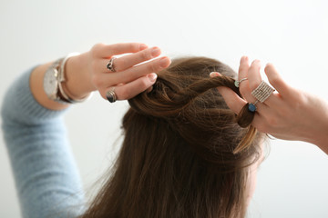 Fototapeta premium Beautiful young woman with stylish bijouterie doing her hair on white background